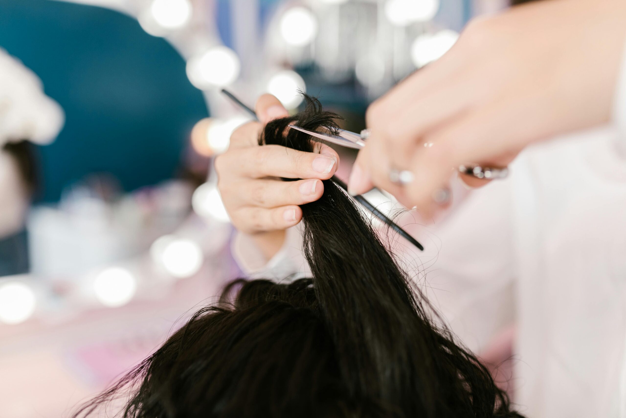 Ein Closeup-Bild einer Friseurin, die gerade die Spitzen einer dunkelhaarigen Kundin schneidet