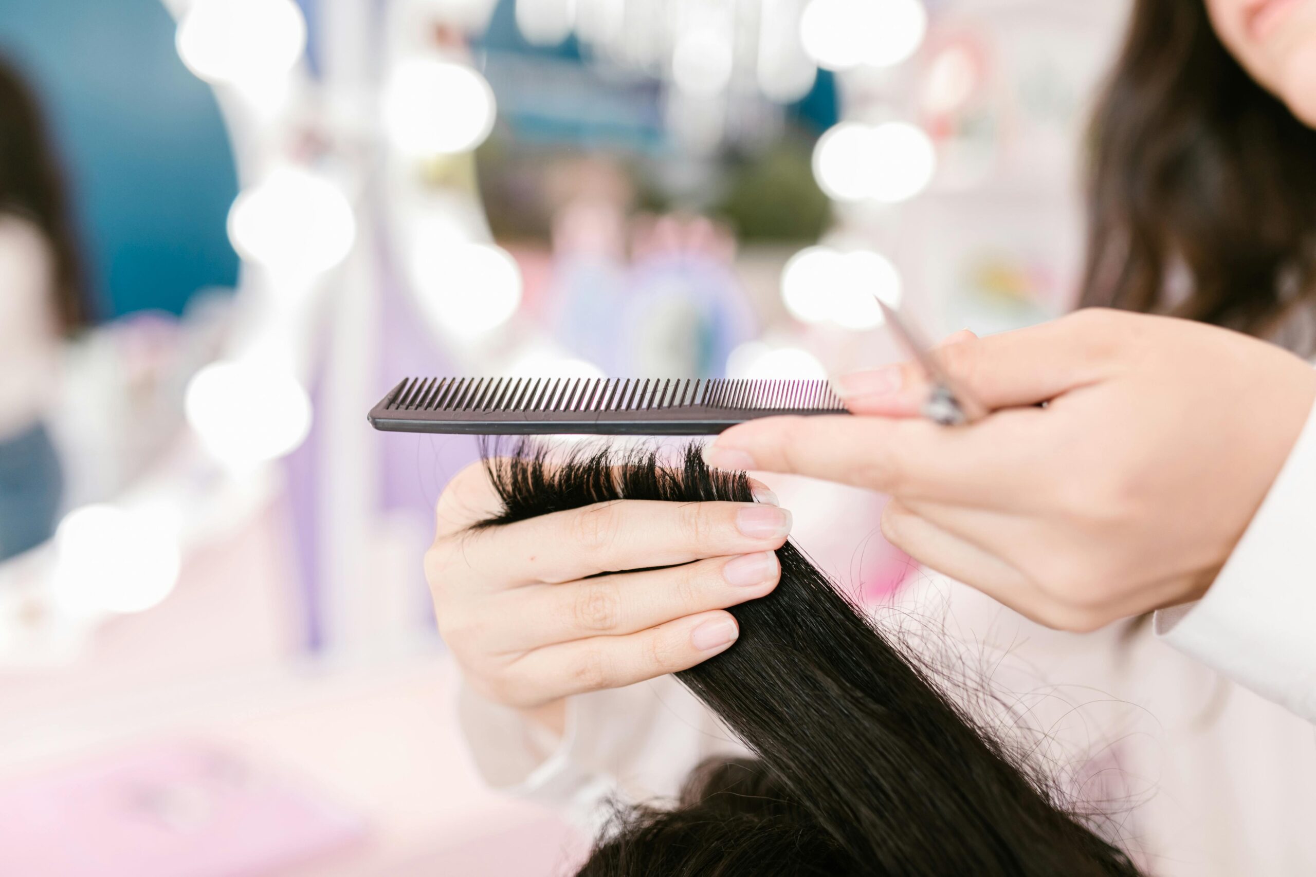 Ein Closeup-Bild einer Friseurin, die gerade die Spitzen einer dunkelhaarigen Kundin schneidet